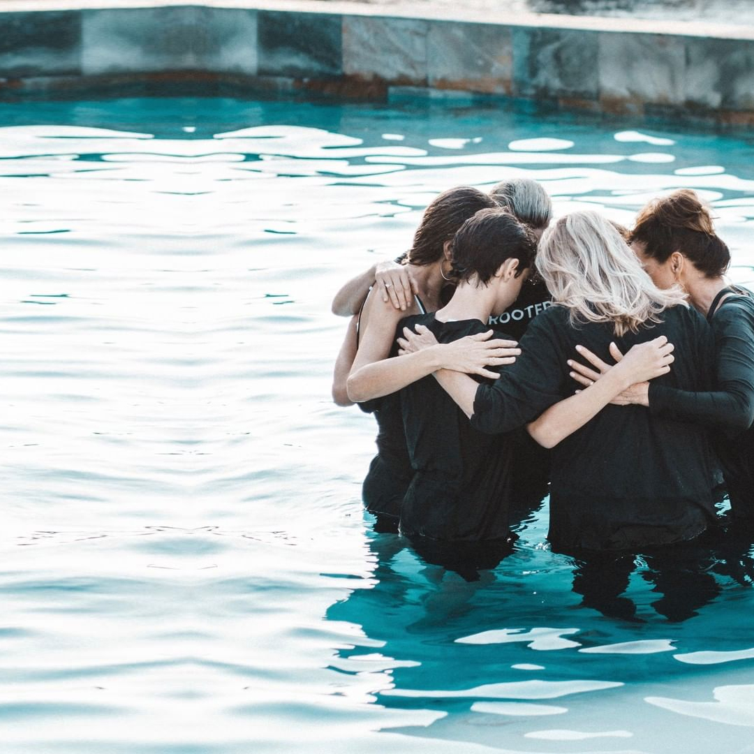 A group huddling together in a pool and praying